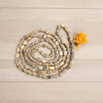 Natural Tulsi Kantha Mala with large round beads, arranged neatly with a central Guru bead on a wooden background