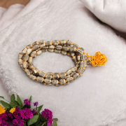 Natural Tulsi Kantha Mala with large round beads, arranged neatly with a central Guru bead on a wooden background