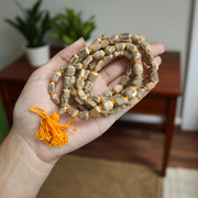 Natural Tulsi Kantha Mala with large round beads, arranged neatly with a central Guru bead on a wooden background