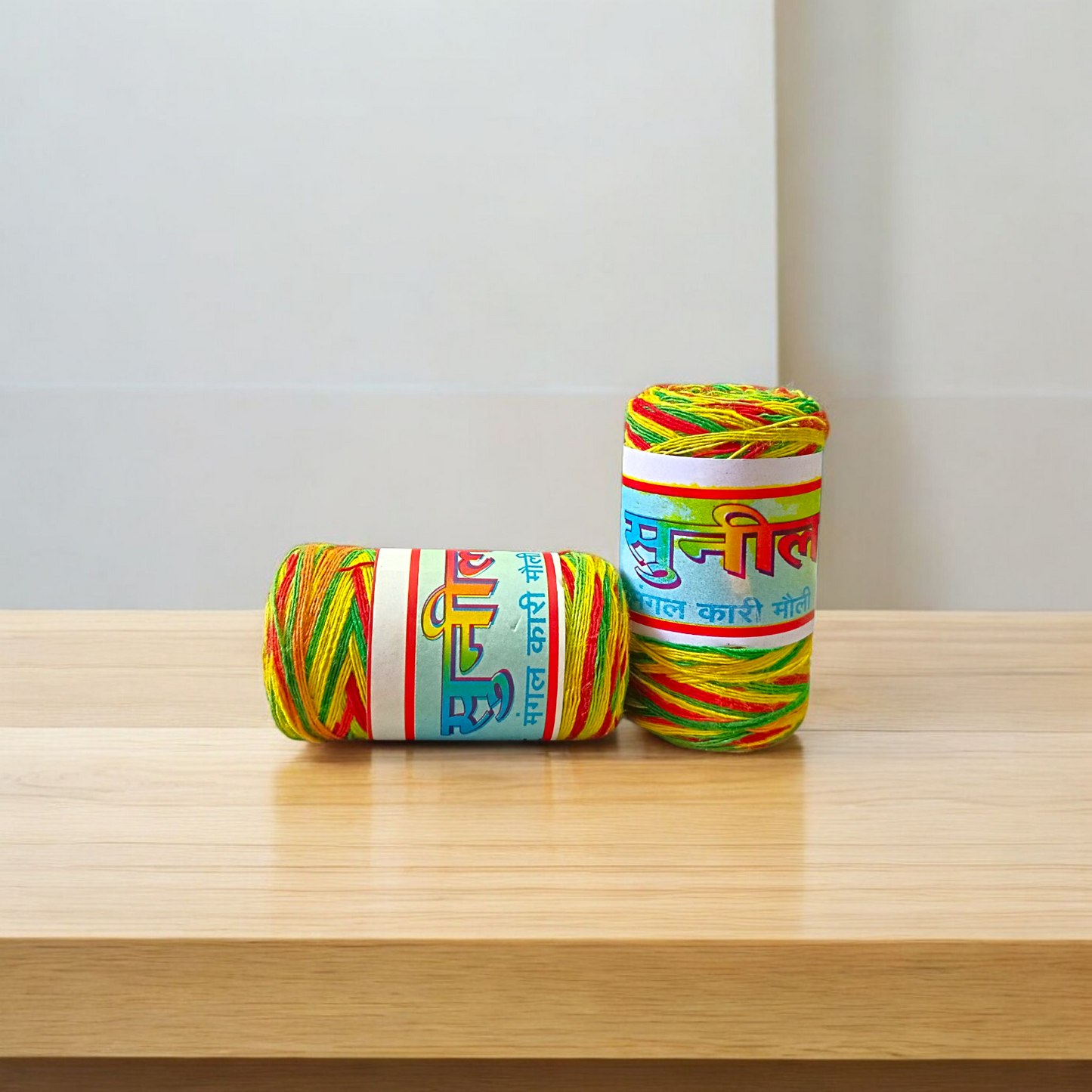 Pack of 2 multi-colored cotton moli threads with red, yellow, and green twists, neatly coiled for pooja use