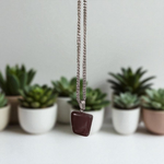 Polished deep red Almandine Garnet pendant with stainless steel chain, designed for men and women, displayed on a neutral surface