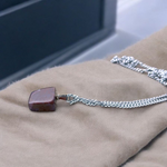Polished deep red Almandine Garnet pendant with stainless steel chain, designed for men and women, displayed on a neutral surface