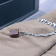 Polished deep red Almandine Garnet pendant with stainless steel chain, designed for men and women, displayed on a neutral surface
