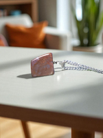 Polished deep red Almandine Garnet pendant with stainless steel chain, designed for men and women, displayed on a neutral surface