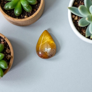 Polished natural brown Tiger Eye Stone with golden shimmer, placed on a white surface for healing and meditation purposes