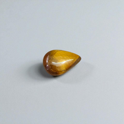 Polished natural brown Tiger Eye Stone with golden shimmer, placed on a white surface for healing and meditation purposes