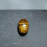 Polished natural brown Tiger Eye Stone with golden shimmer, placed on a white surface for healing and meditation purposes