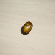 Polished natural brown Tiger Eye Stone with golden shimmer, placed on a white surface for healing and meditation purposes
