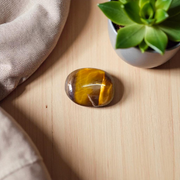 Polished natural brown Tiger Eye Stone with golden shimmer, placed on a white surface for healing and meditation purposes