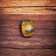 Polished natural brown Tiger Eye Stone with golden shimmer, placed on a white surface for healing and meditation purposes