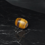 Polished natural brown Tiger Eye Stone with golden shimmer, placed on a white surface for healing and meditation purposes