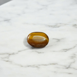 Polished natural brown Tiger Eye Stone with golden shimmer, placed on a white surface for healing and meditation purposes