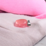 Polished rose quartz tumble pendant with silver chain, displayed on a neutral background, highlighting soft pink color and smooth finish