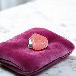 Polished rose quartz tumble pendant with silver chain, displayed on a neutral background, highlighting soft pink color and smooth finish
