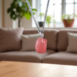 Polished rose quartz tumble pendant with silver chain, displayed on a neutral background, highlighting soft pink color and smooth finish