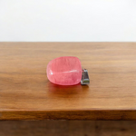 Polished rose quartz tumble pendant with silver chain, displayed on a neutral background, highlighting soft pink color and smooth finish