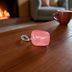 Polished rose quartz tumble pendant with silver chain, displayed on a neutral background, highlighting soft pink color and smooth finish