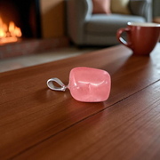Polished rose quartz tumble pendant with silver chain, displayed on a neutral background, highlighting soft pink color and smooth finish