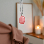 Polished rose quartz tumble pendant with silver chain, displayed on a neutral background, highlighting soft pink color and smooth finish