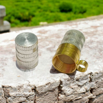 Pure brass and silver cylindrical taweez with intricate design, displayed alongside a Bhojpatra prayer sheet