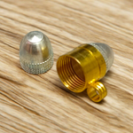 Set of 5 brass and silver tube-shaped taweez displayed with Bhojpatra prayer sheets in the background