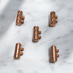 Set of 5 pure copper cylindrical taweez with Bhojpatra prayer sheets arranged on a neutral background