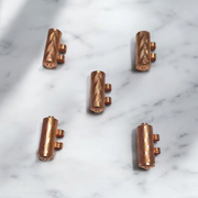 Set of 5 pure copper cylindrical taweez with Bhojpatra prayer sheets arranged on a neutral background