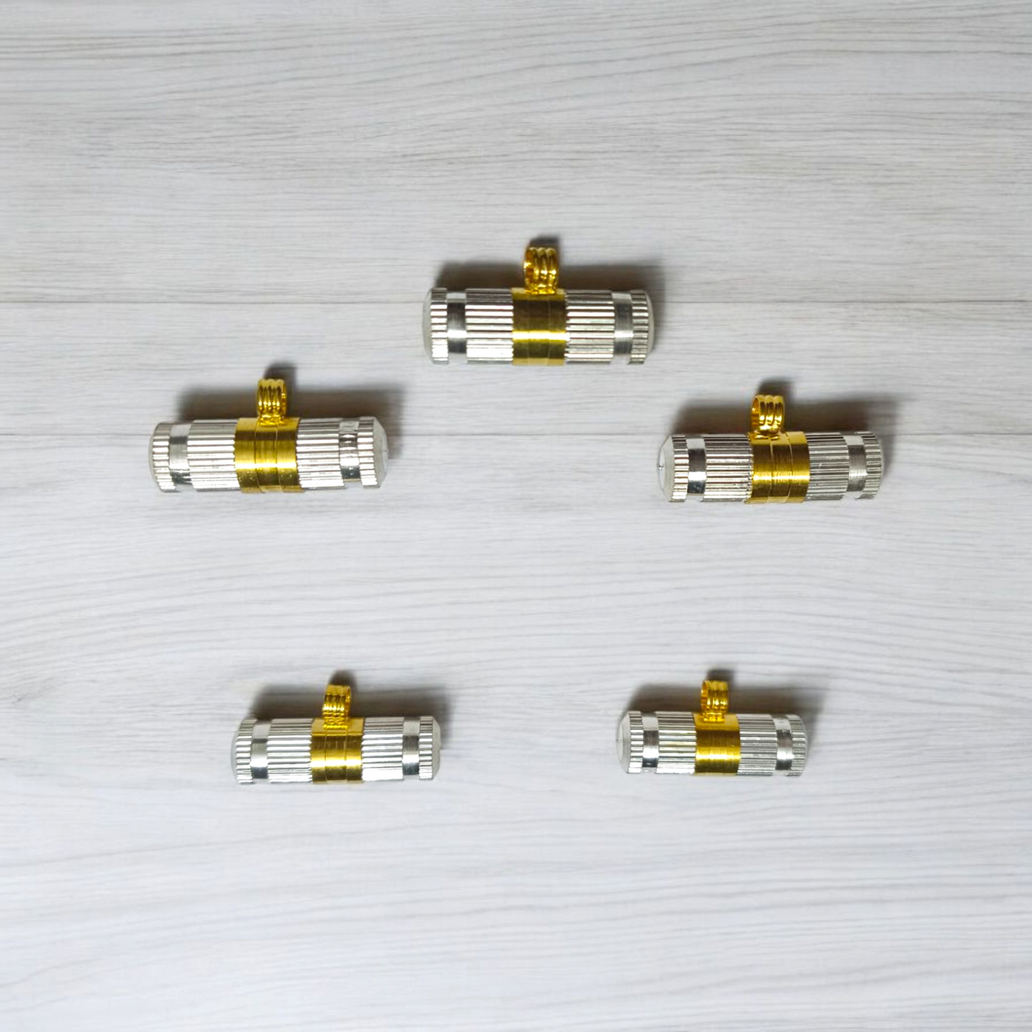 Set of 5 silver and golden Taweez amulets with detailed craftsmanship and a rolled Bhojpatra sheet beside them