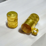 Set of five golden metal taweez cylinders placed neatly beside rolled Bhojpatra sheets on a white surface