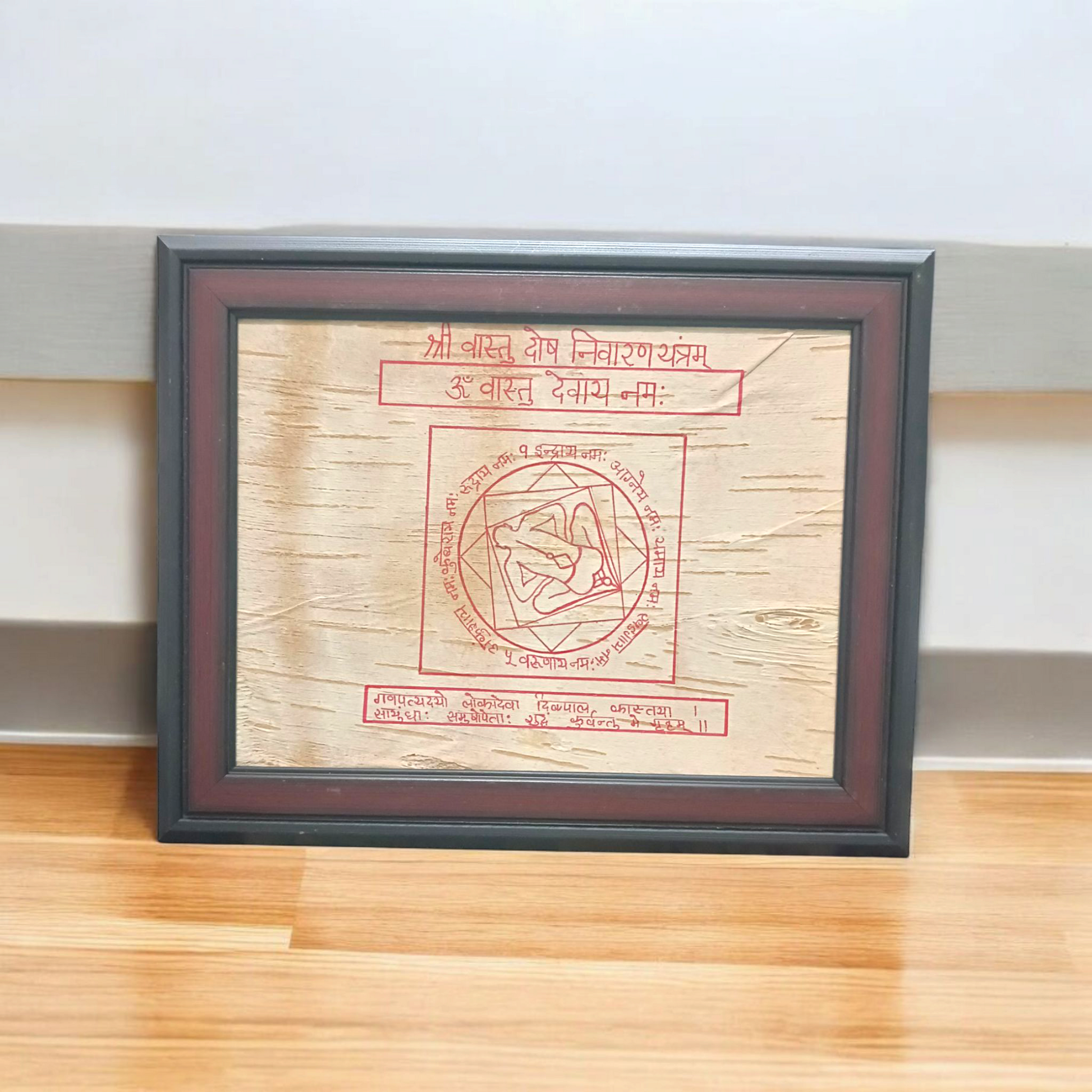 Shri Vastu Dosh Nivaran Yantra inscribed on Bhojpatra and framed in a premium wooden frame with a golden finish, placed on a decorative background