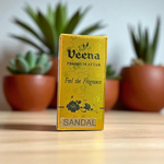 Small glass vial of 2ML Sandal Attar by Veena, MALAWALA brand, with golden cap and traditional label, placed on a wooden background with sandalwood chips