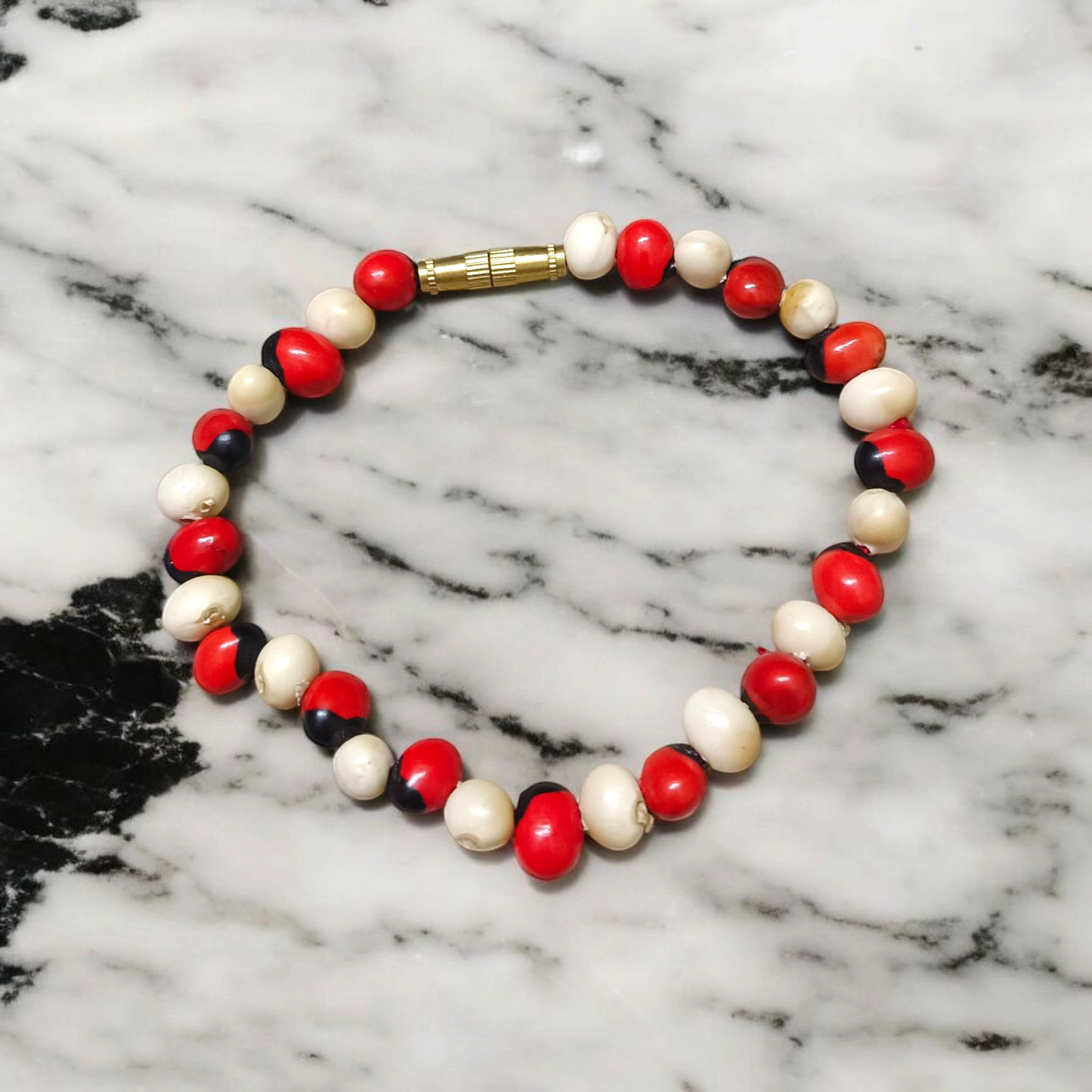 Stretchable bracelet made of natural red and white Gunja seeds, 5mm beads, displayed on a white background