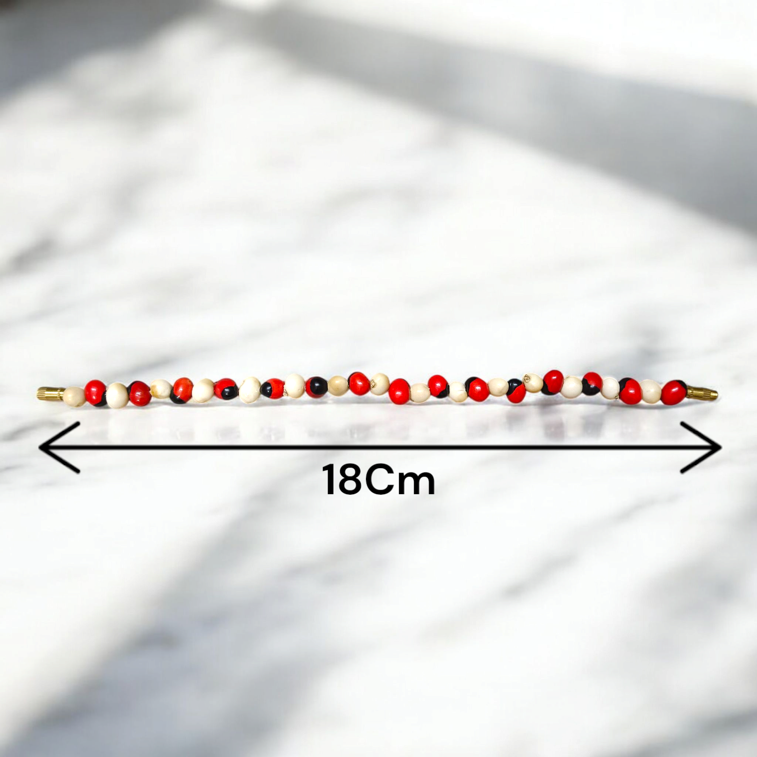 Stretchable bracelet made of natural red and white Gunja seeds, 5mm beads, displayed on a white background