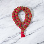 Traditional 5 Mukhi Rudraksha Kantha Mala with 108 beads, laid in a spiral on a wooden surface