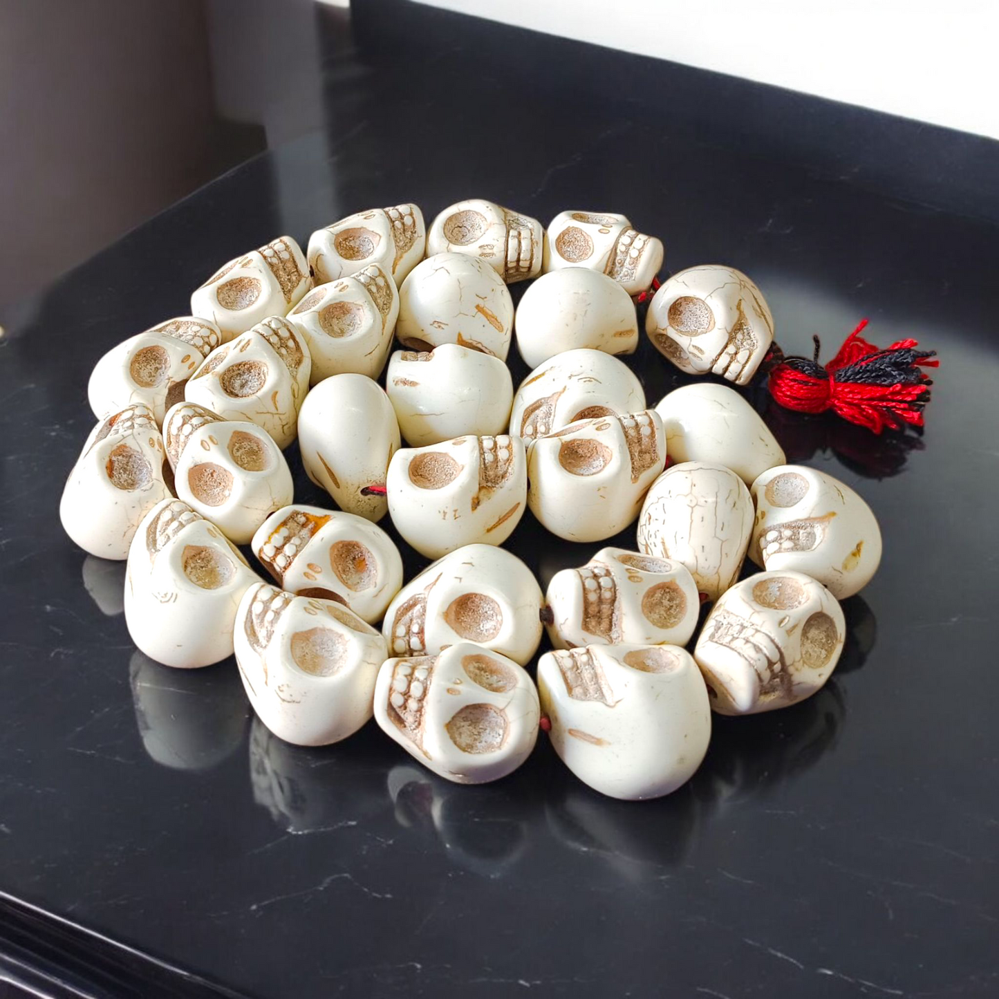Traditional Nar Mund Mala with skull-shaped beads tied in red thread, arranged on a dark spiritual altar cloth