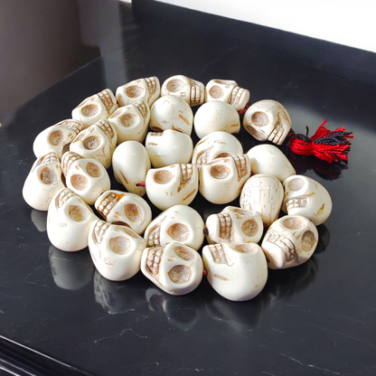 Traditional Nar Mund Mala with skull-shaped beads tied in red thread, arranged on a dark spiritual altar cloth