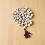 Traditional Nar Mund Mala with skull-shaped beads tied in red thread, arranged on a dark spiritual altar cloth