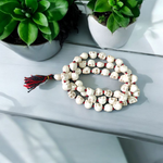 Traditional Nar Mund Mala with skull-shaped beads tied in red thread, arranged on a dark spiritual altar cloth