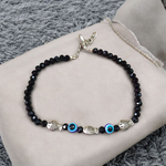 Unisex black crystal beads anklet featuring protective Evil Eye and lucky Fish charms, handcrafted for spiritual style and daily wear