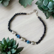 Unisex black crystal beads anklet featuring protective Evil Eye and lucky Fish charms, handcrafted for spiritual style and daily wear