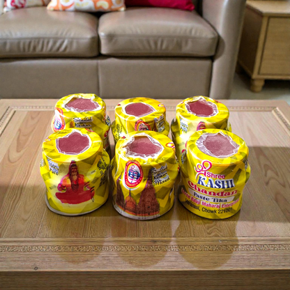 Yellow chandan paste container used for tilak, puja, and religious rituals