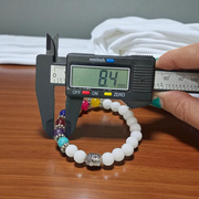 A handcrafted 7 Chakra Bracelet with White Agate and Howlite beads arranged in a circular elastic design, ideal for spiritual healing and meditation